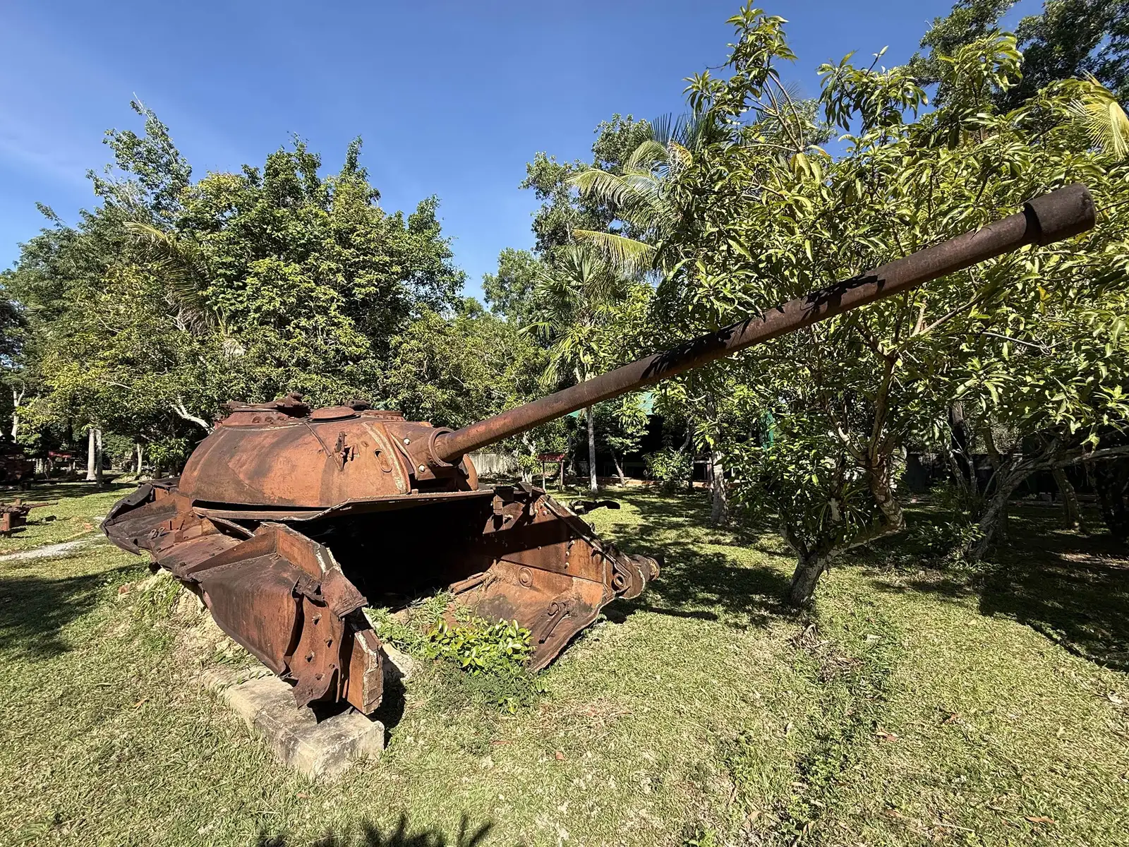 Tourelle de char au canon incliné, caisse ouverte par une explosion, sous les arbres